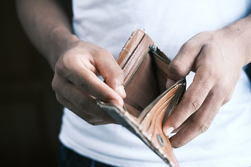 A person holding an empty, worn-out wallet, emphasizing financial hardship or lack of funds.