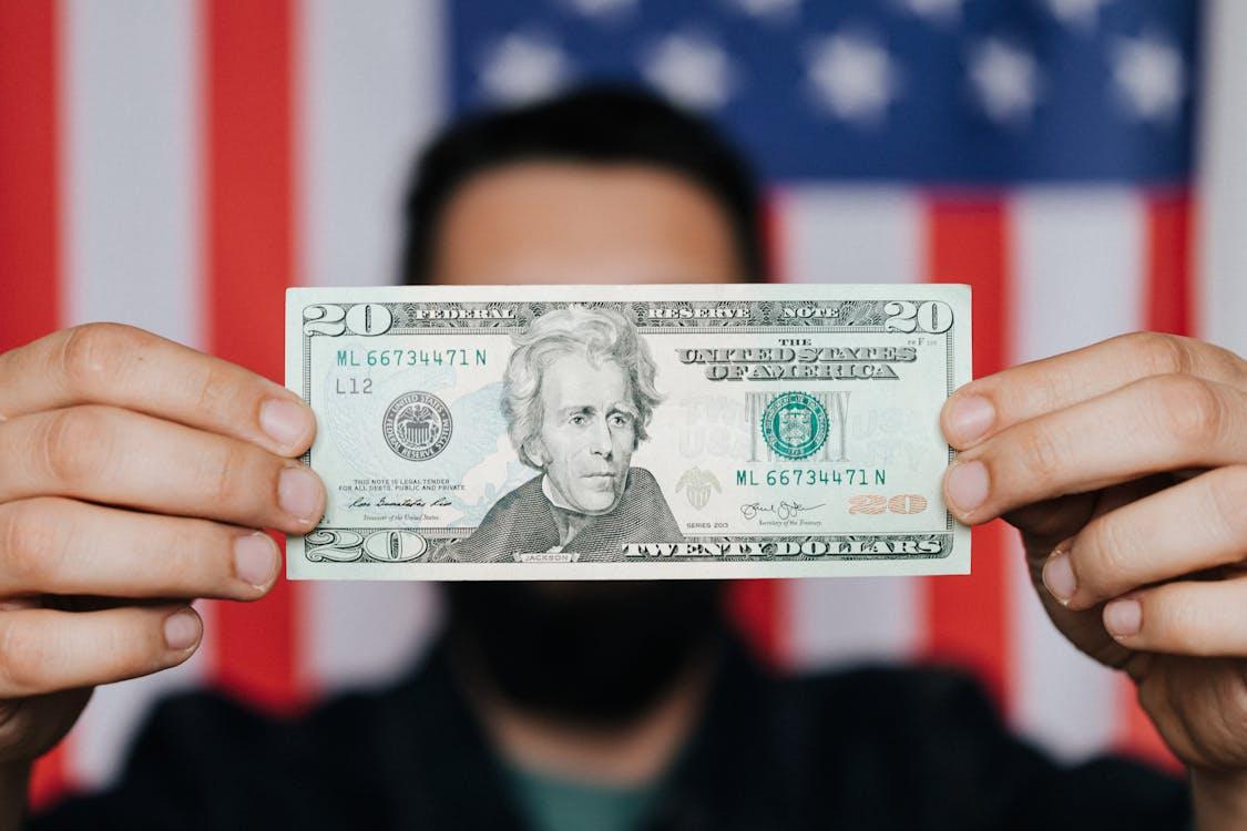 Unrecognizable person holding a twenty-dollar bill
