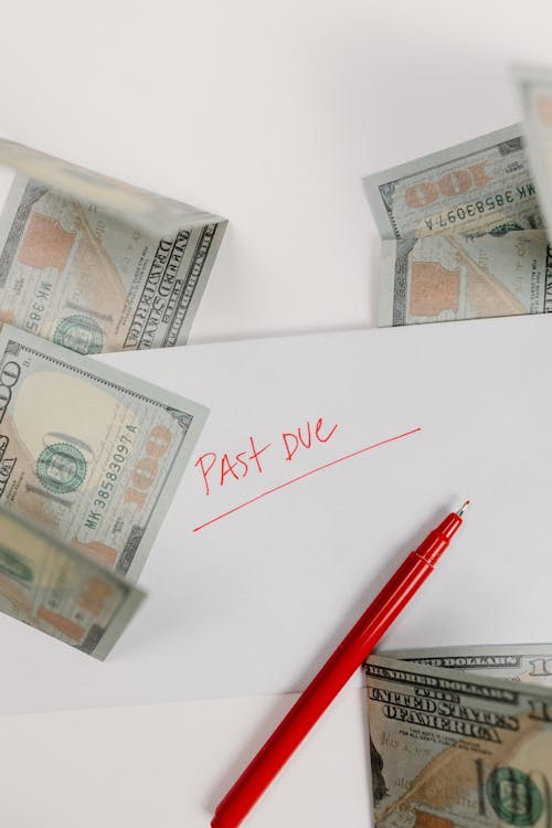 dollar bills scattered on a paper with 'past due' written on it