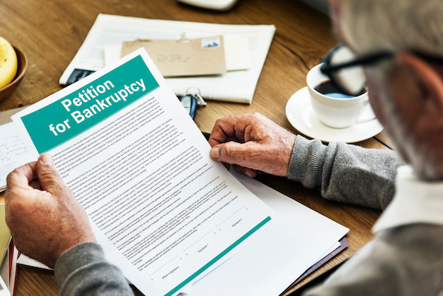 An elderly person carefully reading a bankruptcy petition, assessing their financial options.