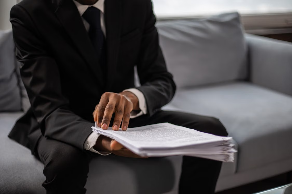 A person sitting on a couch and holding documents