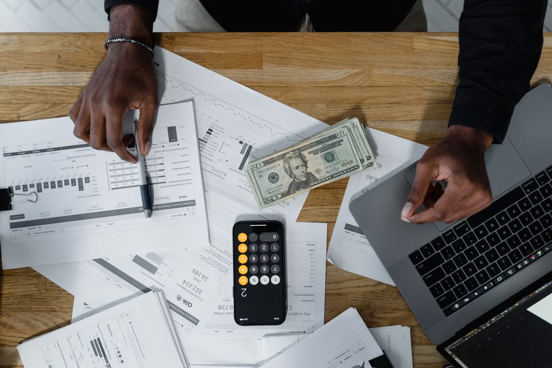 Documents, laptop, money, and a smartphone on a table